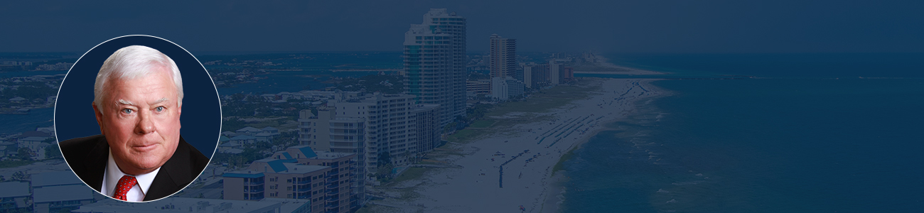 Attorney Jule Herbert with an Aerial view of a beach with waves, surrounded by buildings in the background